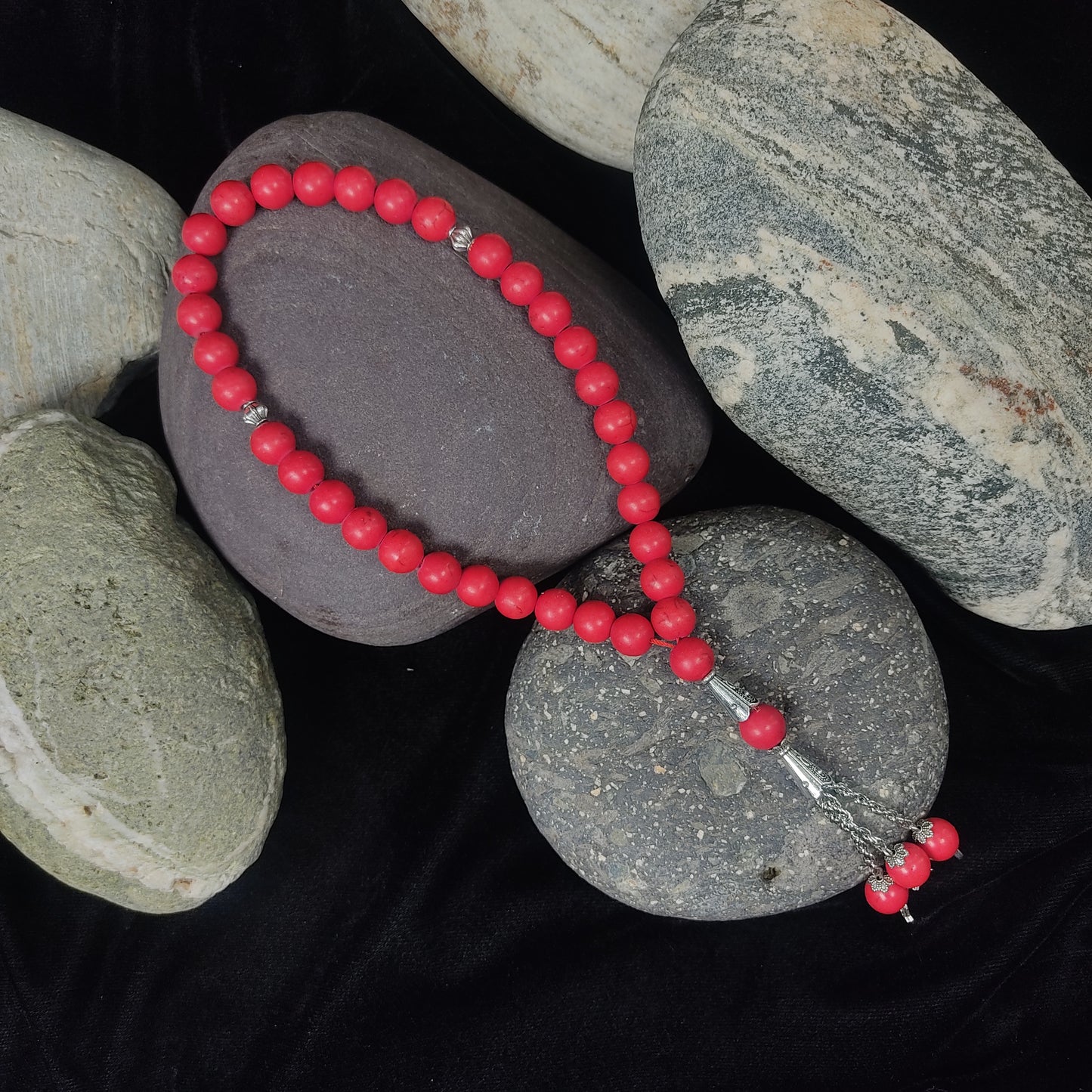 Red beaded bracelet on gray stones