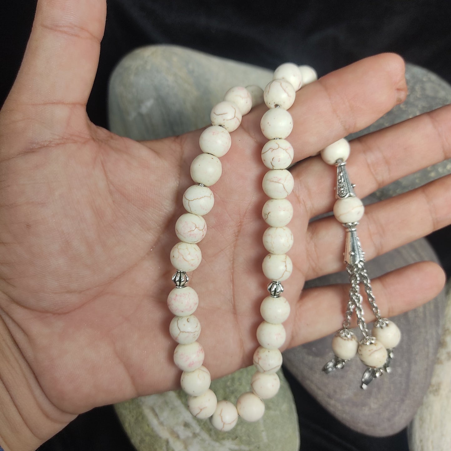 White beaded bracelet on a hand with a blurred natural background